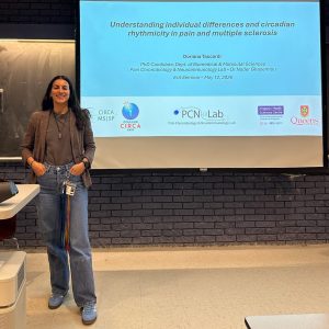 Doriana standing next to her title slide on a projector