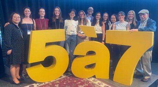 Many ghasemlou lab members standing behind large yellow letters that read 5 a 7.