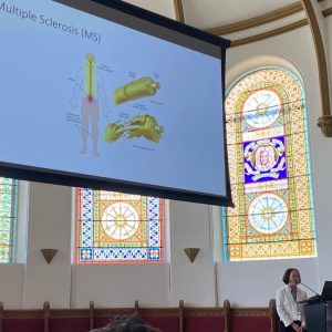 vina giving an oral presentation. most of the picture is her slide that says "Multiple Sclerosis", with Vina in the bottom right corner.